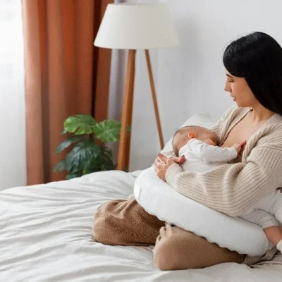 a mother sitting on the bed while holding her sleeping baby