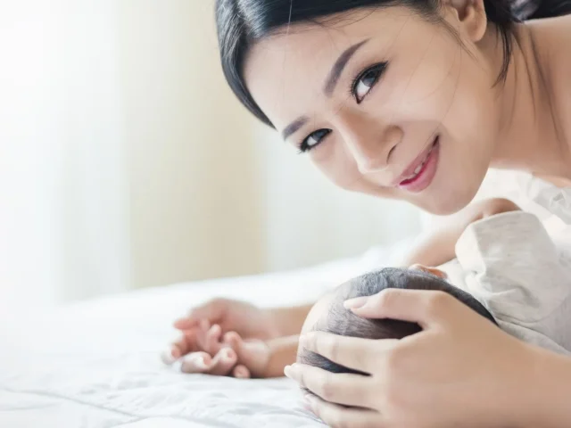 New mum bonding with her newborn during the confinement period, reflecting gentle postnatal wellness support at home.