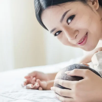 New mum bonding with her newborn during the confinement period, reflecting gentle postnatal wellness support at home.