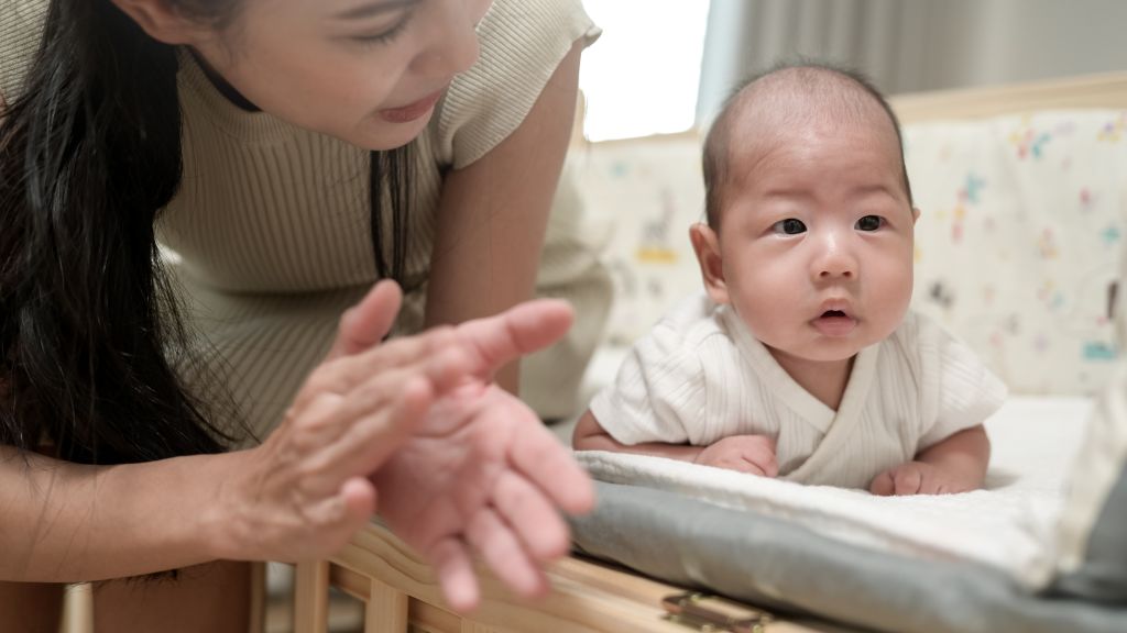 Caregiver from a nanny agency in Singapore supporting infant development during supervised tummy time at home