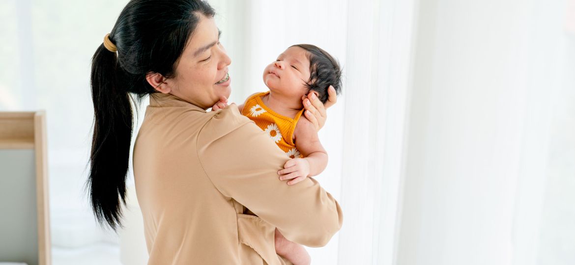 Caregiver from a nanny agency in Singapore holding and comforting a newborn at home