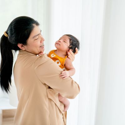 Caregiver from a nanny agency in Singapore holding and comforting a newborn at home