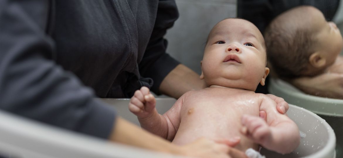 Confinement nanny in Singapore bathing a newborn baby, providing gentle hygiene care and professional postnatal support at home