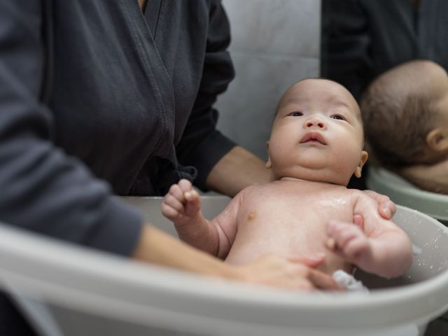 Confinement nanny in Singapore bathing a newborn baby, providing gentle hygiene care and professional postnatal support at home