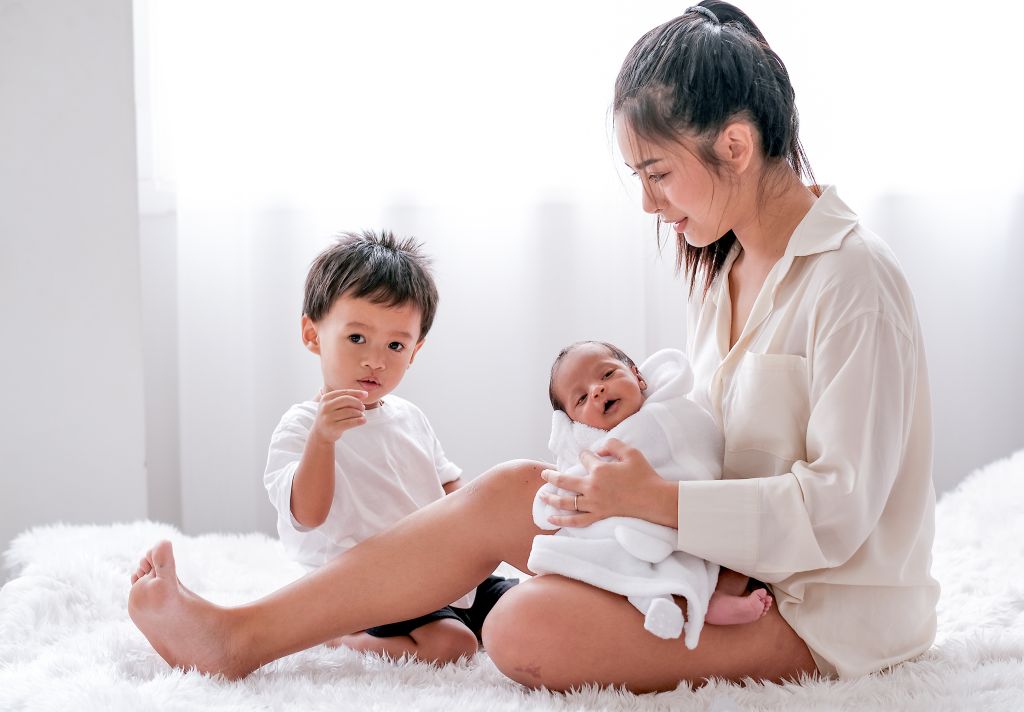 Family newborn care supported by a nanny agency in Singapore, with a caregiver assisting in a multi-child home setting