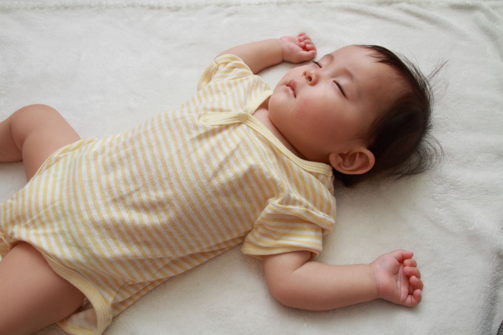 Sleeping newborn resting on a soft bed, cared for by a confinement nanny in Singapore during the baby’s postnatal recovery period