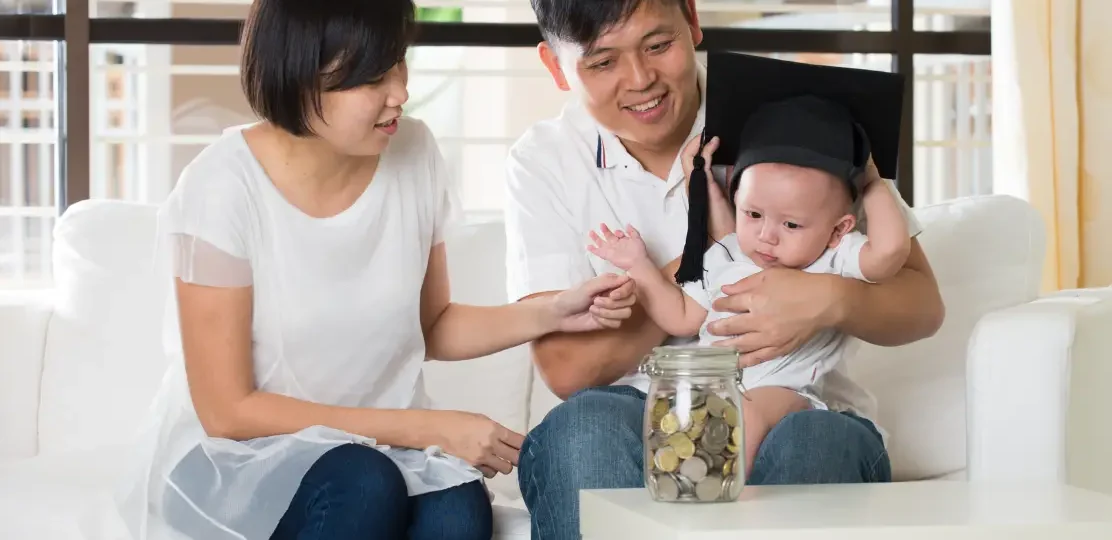 Parents holding their newborn child with a toga hat on his head. A nanny in Singapore can help build confidence with parents to look after their child on their own.