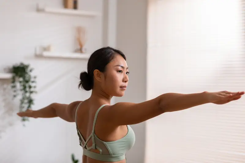 A mother stretching out her arms for a yoga pose. Exercise is essential for mothers recovering postpartum.