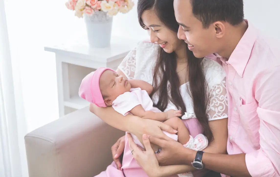 Family wearing pink, consisting of first time parents and a newborn baby